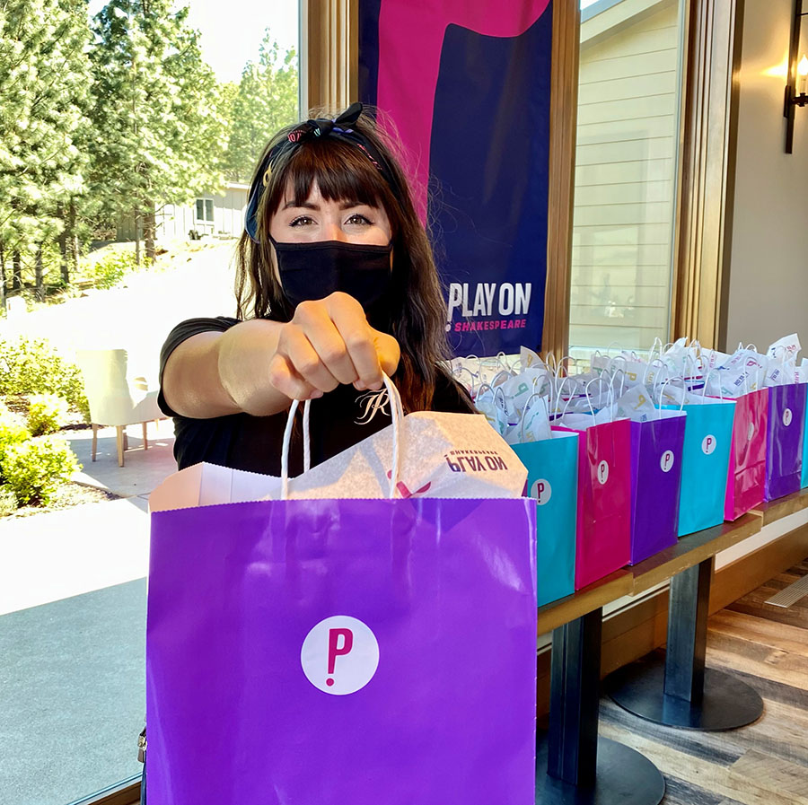 A woman holding out a purple gift bag with the Play On logo